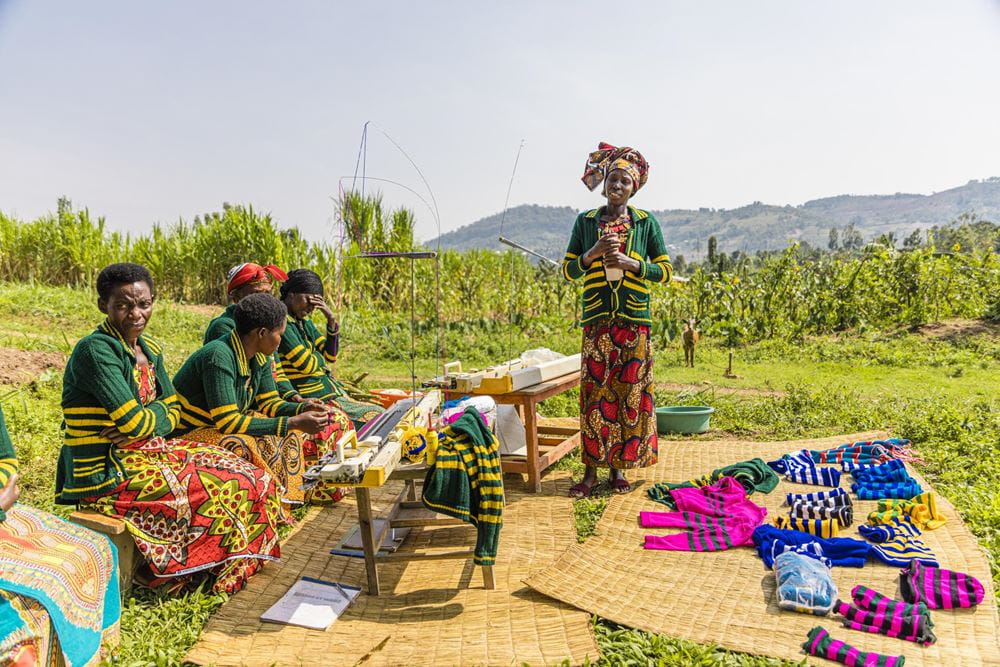 Eine Frauengruppe auf einer Wiese, vor sich Strickmaschinen und Strickkleidung (Quelle: Martin Bondzio)